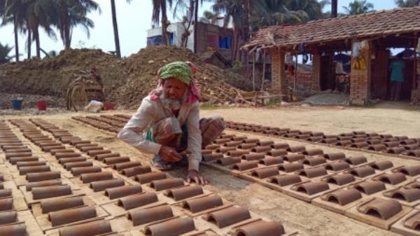 A worker lays out clay-made roofing tiles under the sun for drying in Murarikati village of Satkhira’s Kolaroya Sadar upazila. The photo was taken recently. Photo: TBS
